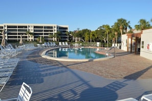 A pool area with lounge chairs and a building in the background.