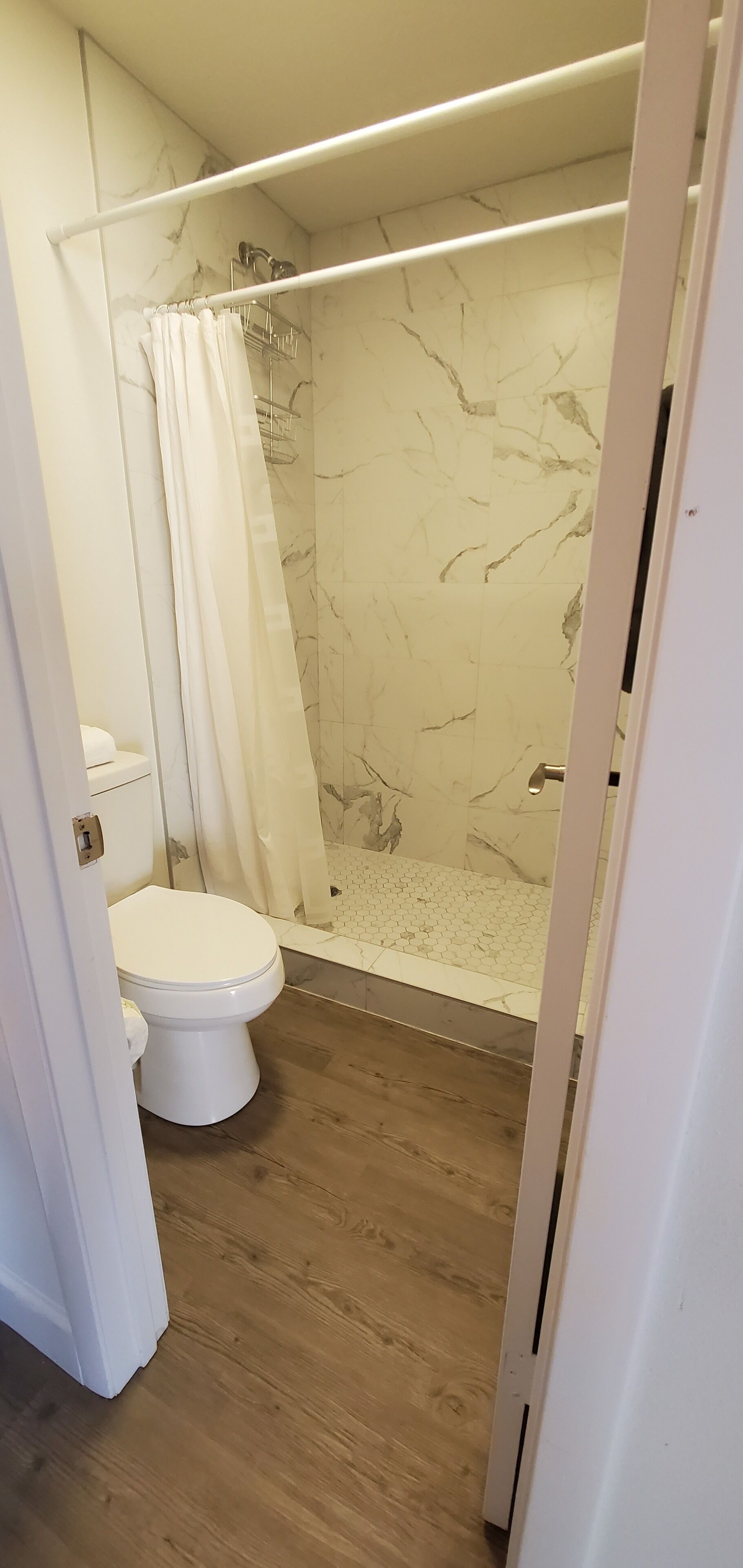 Un baño con ducha, inodoro y paredes de mármol.