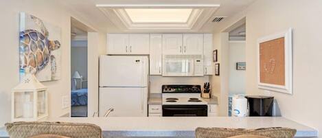 A modern kitchen with white cabinets, a central island, and a ceiling light.