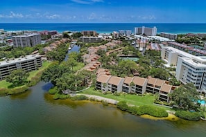 An aerial view of a coastal hotel area with multiple buildings, a river, and a beach in the background.