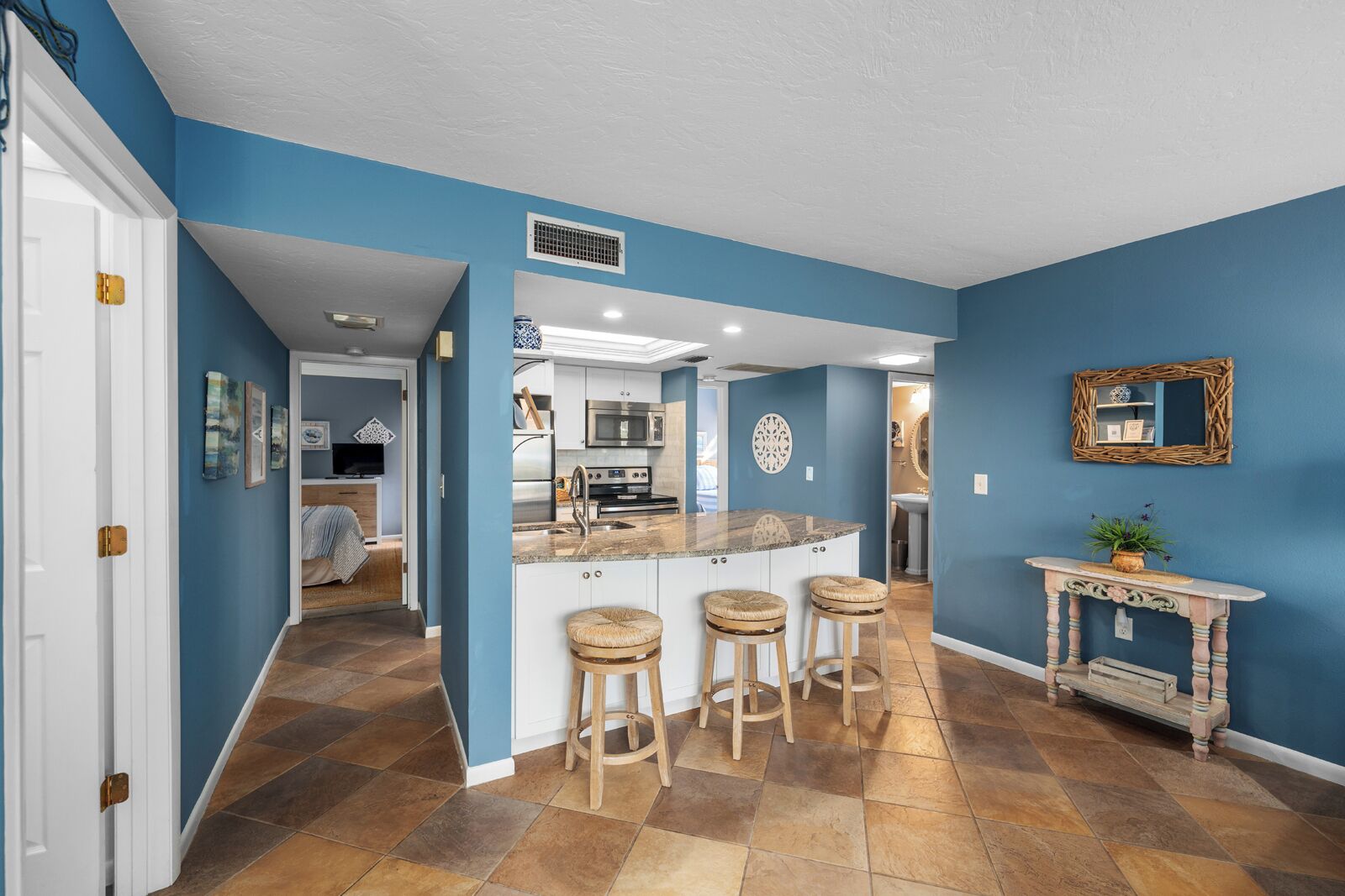 A modern kitchen with a central island, bar stools, and a decorative console table.