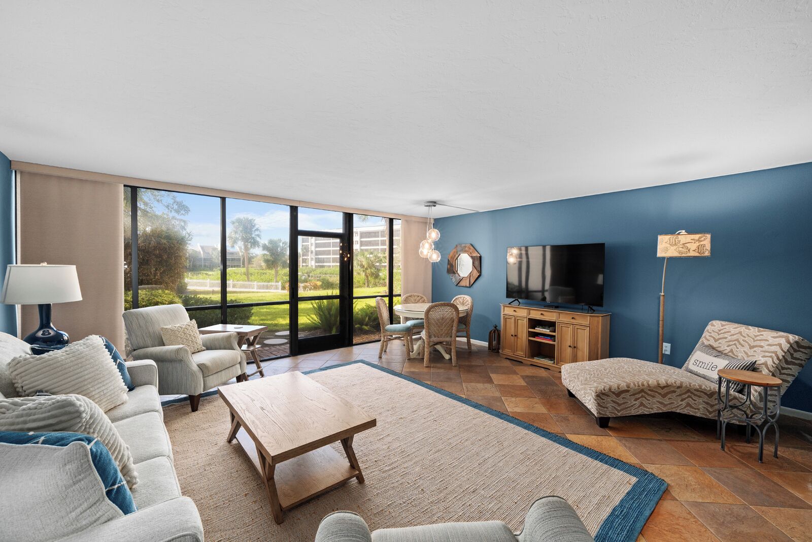 A spacious living room with a large TV, comfortable seating, and a view of the outdoors.