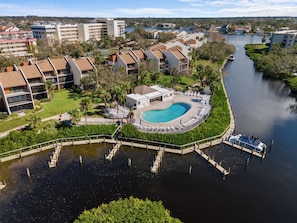 A resort with a swimming pool surrounded by lounge chairs and a dock.