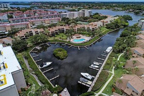 An aerial view of a marina with boats docked, surrounded by residential buildings and a central island with a pool. - Midnight Cove II 620D - Tropical Condo in Siesta Key (Siesta Key)