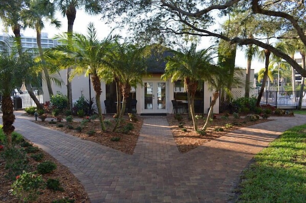 A pathway leading to a building with a white facade and a covered entrance. - Midnight Cove II 715F - Siesta Key Condo Gorgeous Beach Decor Access to Pool (Siesta Key)