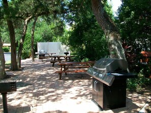 An outdoor patio with picnic tables and a barbecue grill.