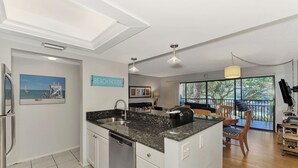 A modern kitchen with a central island, a dining area with a view, and a sign reading "BEACH HOUSE". - Midnight Cove II 822F - Relaxing Vacation Rental in Siesta Key (Siesta Key)