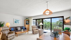 A spacious living room with a sofa, recliners, a dining table, and a balcony with a view. - Midnight Cove II 833F - Siesta Key Condo with Balcony and Marina View! (Siesta Key)