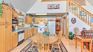 A spacious kitchen with wooden cabinets, a dining table with chairs, and a staircase leading to an upper level. - Murphy Cabin w/ Deck and Stunning Mountain Views (Murphy)
