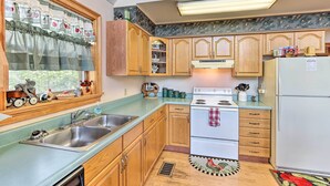 A kitchen with wooden cabinets, a double sink, a stove, and a refrigerator. - Murphy Cabin w/ Deck and Stunning Mountain Views (Murphy)