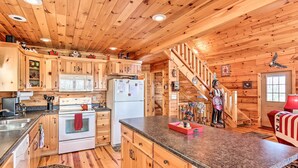 A wooden cabin kitchen with a central island, wooden cabinets, a refrigerator, and a stove. - Murphy Cabin: Wheelchair Accessible w/ Fire Pit! (Murphy)