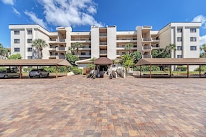 A multi-story hotel with a central entrance, covered parking, and a landscaped courtyard.