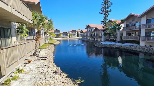 Un canal bordé de bâtiments des deux côtés, avec des balcons et un ciel dégagé.