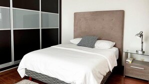 A bedroom with a bed, a nightstand, a lamp, and a sliding door. - Condesa Residence Amsterdam 202 - Hipodromo area (Ciudad de México)