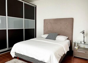 Una camera da letto con un letto, un comodino, una lampada e una porta scorrevole.