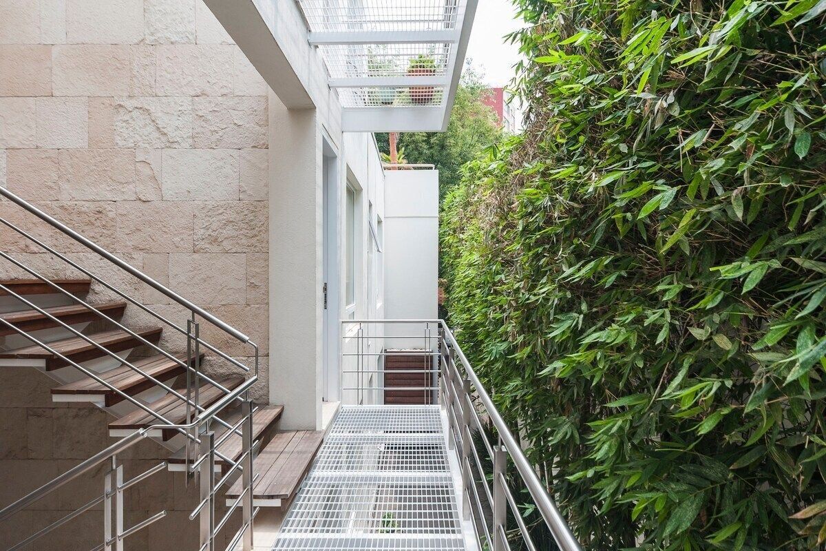 A staircase leading to a building with a metal handrail and a metal grid floor.