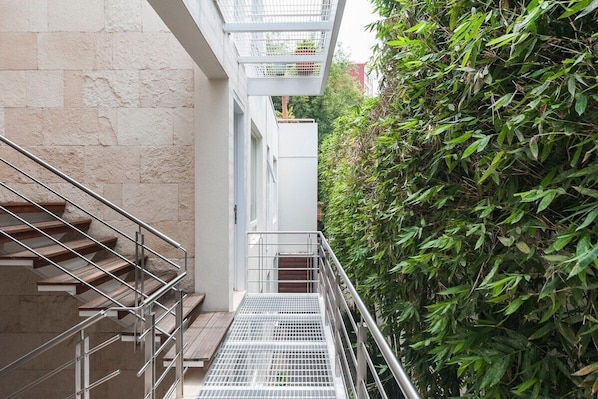 A staircase leading to a building with a metal handrail and a metal grid floor.