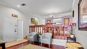 Eine Hotelhalle mit einer Rezeption, zwei Sesseln, einer Holzwand, einem Essbereich und einem Massagetisch.