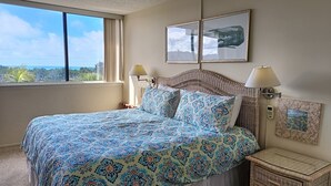 Ein Schlafzimmer mit Bett, Nachttisch, Lampe, Deckenventilator und einem Fenster mit Blick.