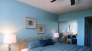 A bedroom with a bed, two bedside lamps, and two framed floral pictures on the wall. - Our House at the Beach E-402 Beach view (Siesta Key)