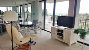 A spacious balcony with a dining area, a sofa, a TV, and a potted plant. - Our House at the Beach E-402 Beach view (Siesta Key)