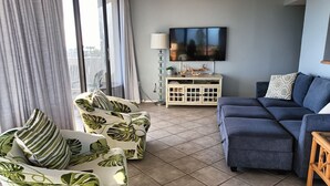 A living room with a sofa, armchairs, a TV, and a cabinet. - Our House at the Beach E-404 Sugar Sands Beach View!! (Siesta Key)