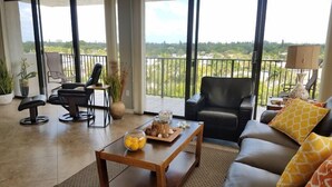 A spacious living area with a balcony, a leather sofa, a coffee table with fruits, and a chair. - Our House at the Beach E-603 Phenomenal Views and Location (Siesta Key)