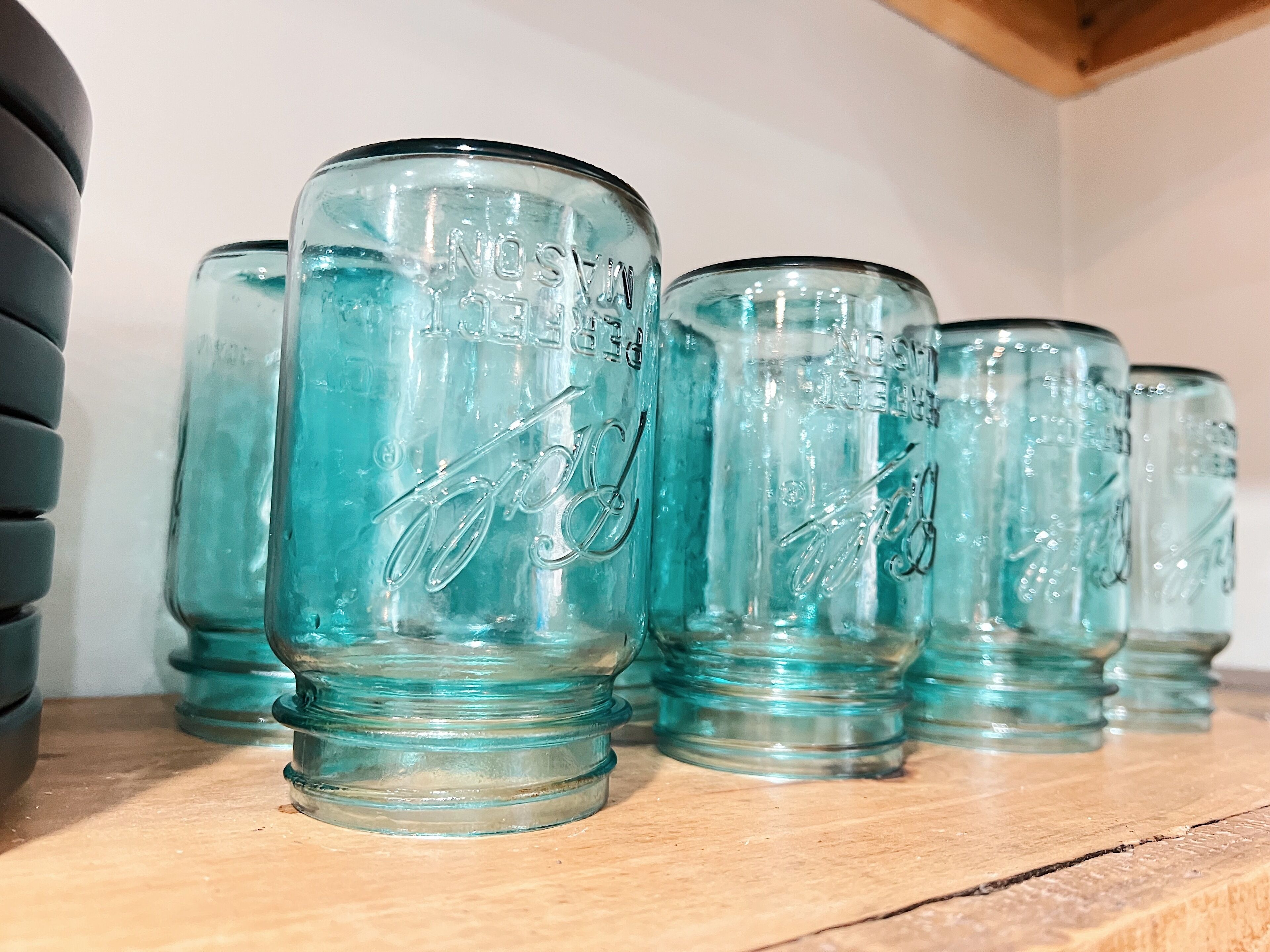 Una hilera de botellas de vidrio transparente con texto en relieve sobre un estante de madera.