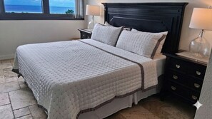 Un lit bien fait, avec une couverture matelassée, une tête de lit sombre et des tables de chevet dotées de lampes.