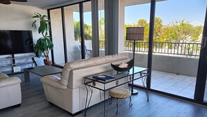 A modern living room with a sofa, a glass coffee table, and a TV. - Next to the Beach - Our House at the Beach W-103 (Siesta Key)