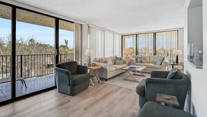 Ein geräumiges Wohnzimmer mit großen Fenstern, einem Balkon und modernem Interieur.