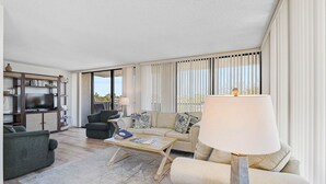 Ein modernes Wohnzimmer mit einer Couch, Sesseln, einem Couchtisch und einem Fernseher.