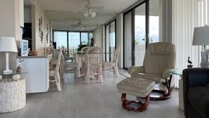 Uma sala de estar espaçosa com área de jantar, uma janela grande e um ventilador de teto.