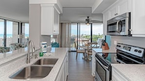 A modern kitchen with a large island, stainless steel appliances, and a view of the ocean.