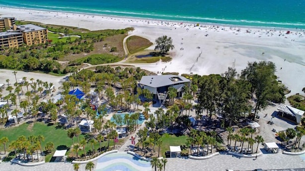 A resort with a beach, pool area, and a large building.
