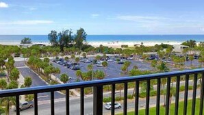 A beachfront parking lot with cars, palm trees, and a view of the beach and ocean. - Our House at the Beach W-701 Best Panoramic Views! (Siesta Key)