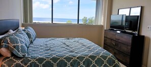 A bedroom with a bed, a dresser, a television, and a window with a view of the sea. - Our House at the Beach W-701 Best Panoramic Views! (Siesta Key)