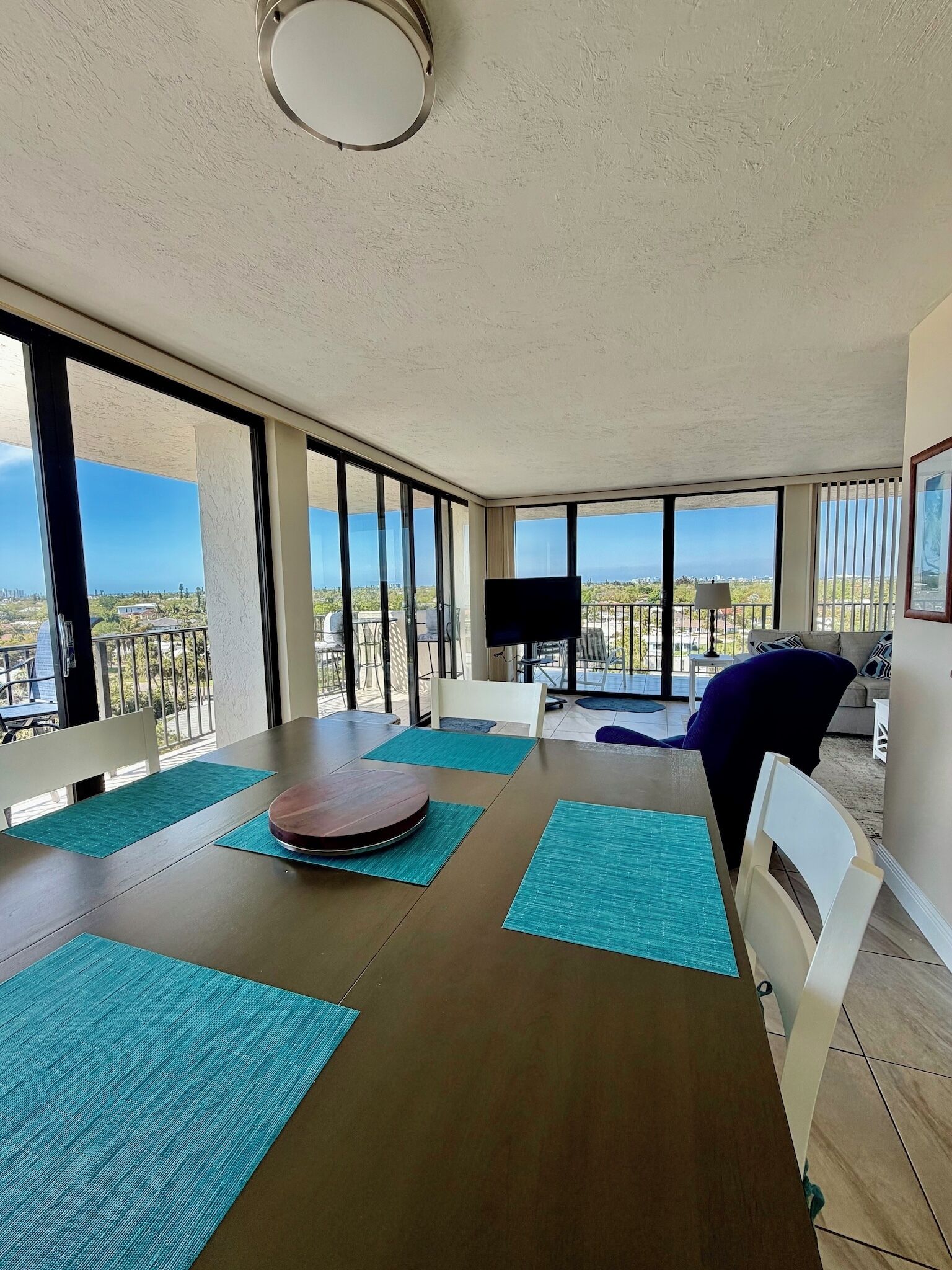 A spacious balcony with a dining area, large windows, and a flat-screen TV.