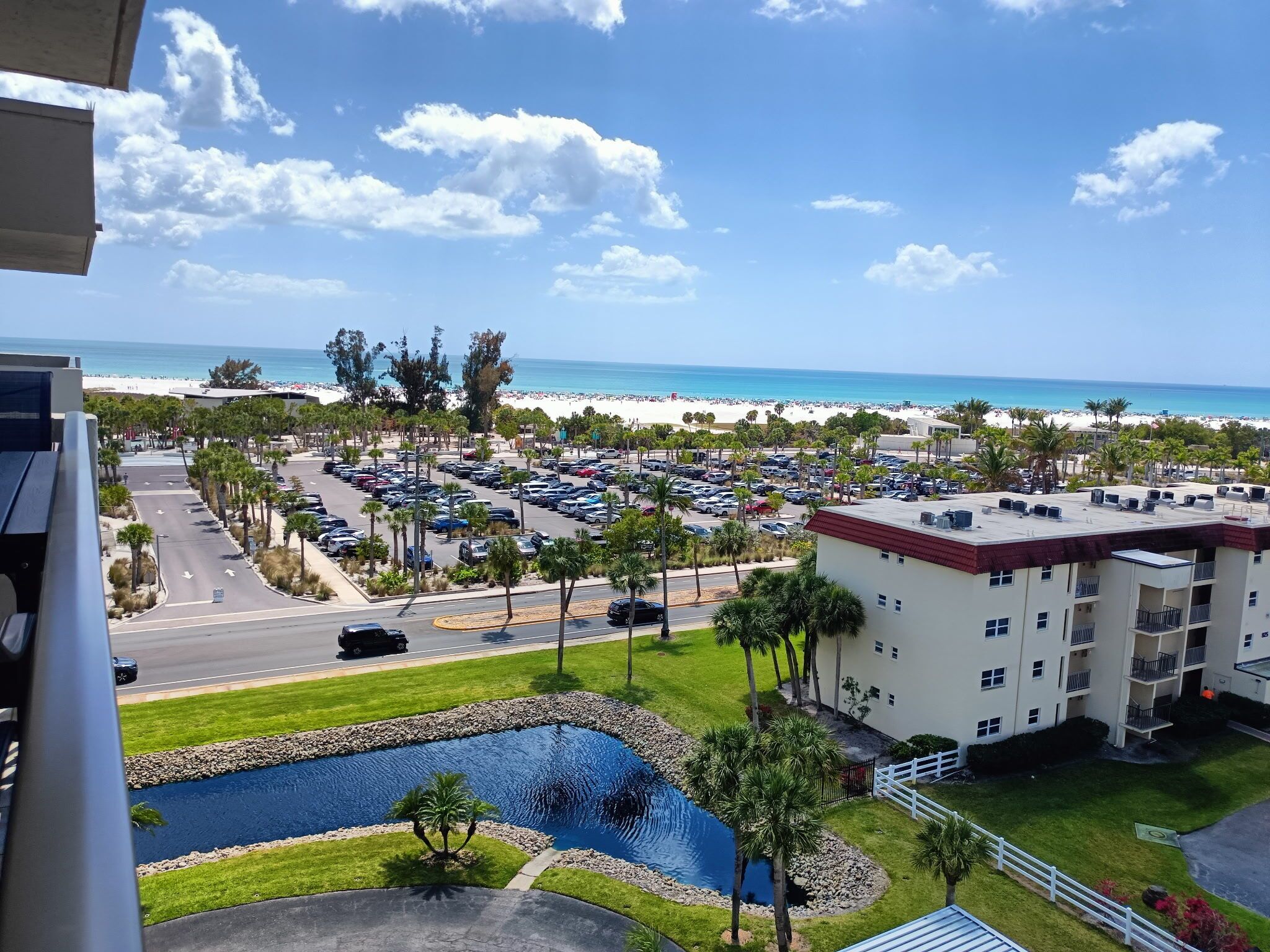 A hotel with a pool, parking lot, and ocean view.