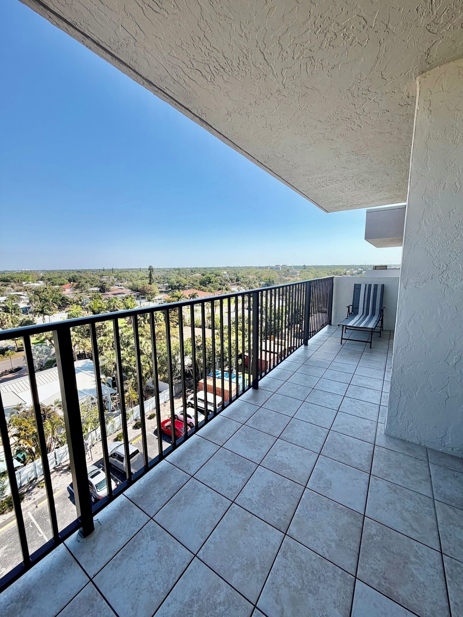 Un balcon donnant sur un parking et des immeubles.