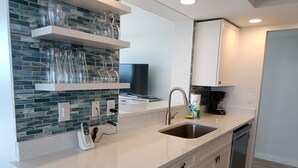 Cuina moderna amb salabost d'granit, vàlib d'acer inoxidable i armaris blancs.