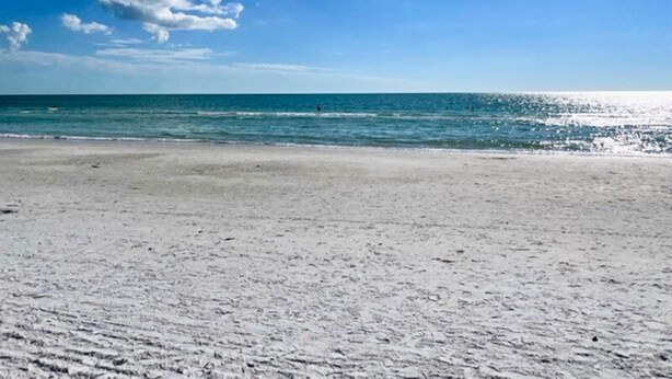 Una playa con cielo despejado y mar tranquilo.