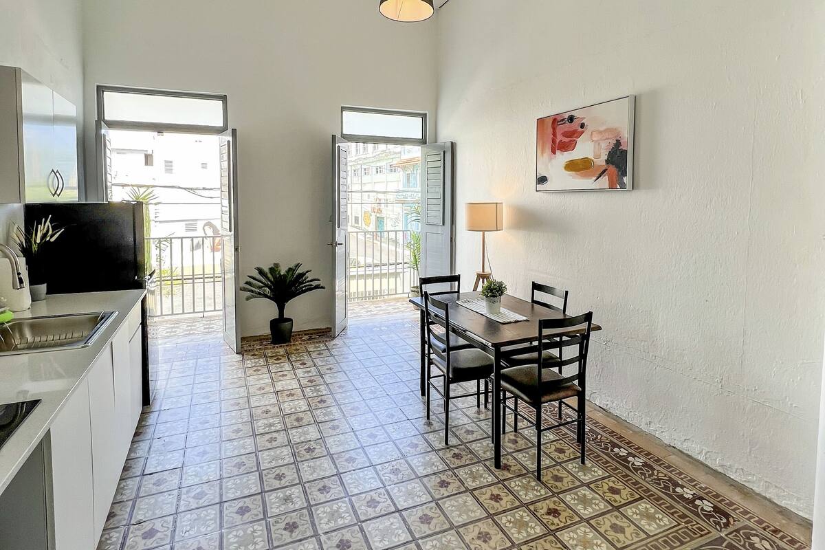 A kitchen with a dining area, a potted plant, and a view through an open door.