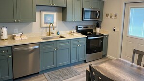 A kitchen with teal cabinets, a stainless steel dishwasher, a microwave, and an oven. - Townhouse with Beach Access, Shared Pool - Siesta Beach House 308 (Siesta Key)