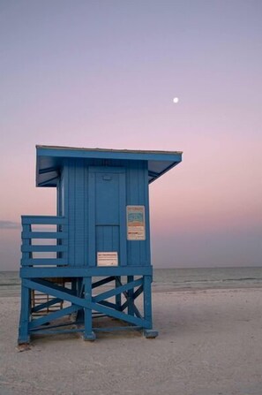 A blue lifeguard tower on a beach with a clear sky and a visible moon. - Sunset Royale - 100- Outdoor Patio directly across from Siesta Key Beach (Siesta Key)