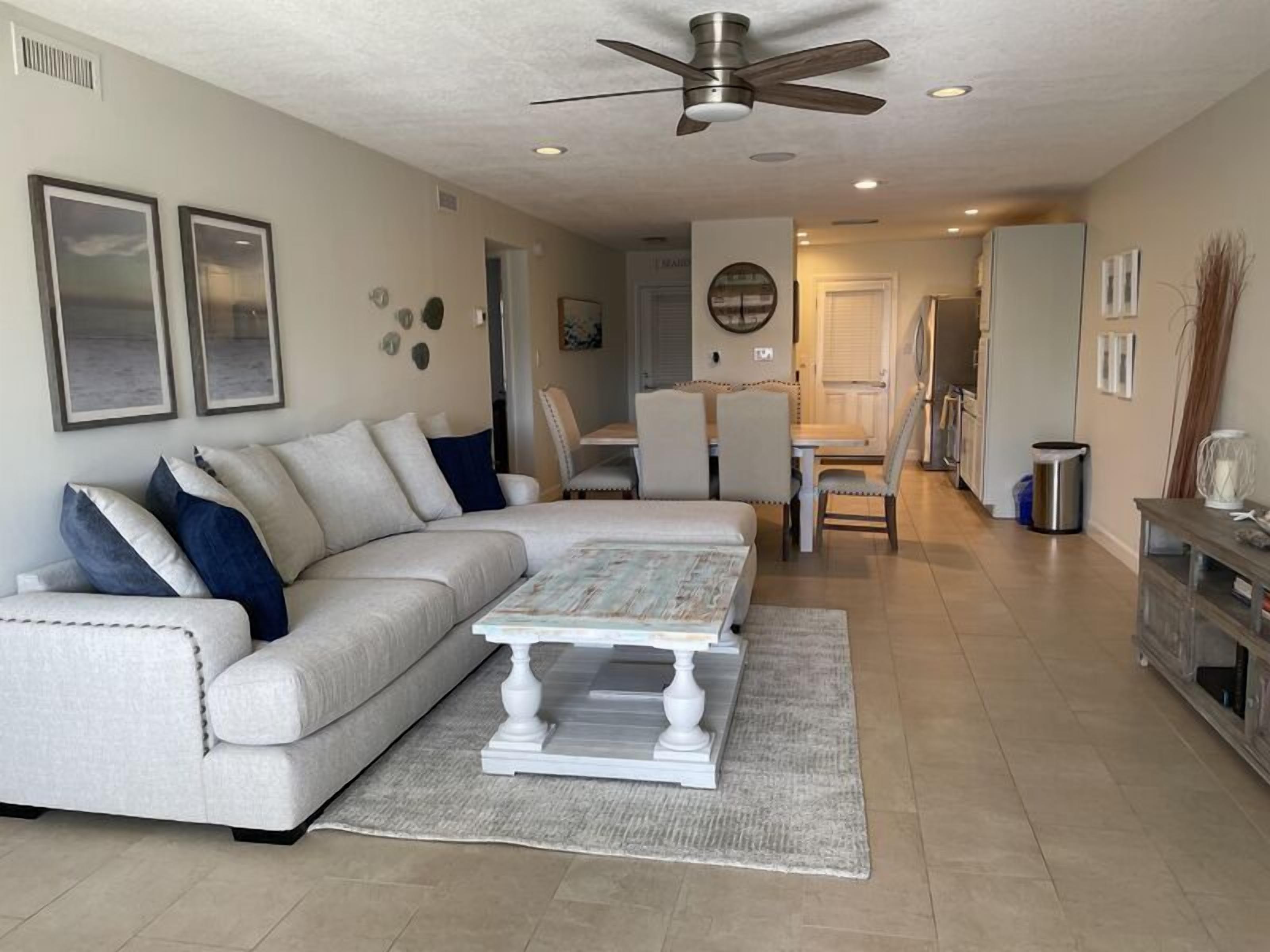 A living room with a sectional sofa, a coffee table, and a dining area with chairs.