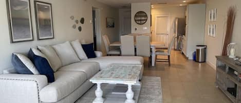 A living room with a sectional sofa, a coffee table, and a dining area with chairs.