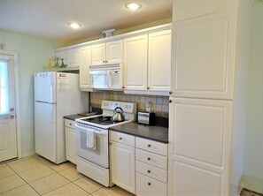 Kitchen features a refrigerator, microwave, stove, and oven, along with a toaster and kettle on the countertop.