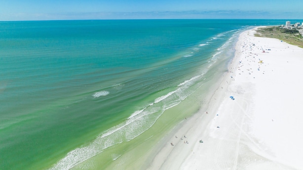 Ein Strand mit weitem, sandigen Ufer und einem klaren, blauen Meer.