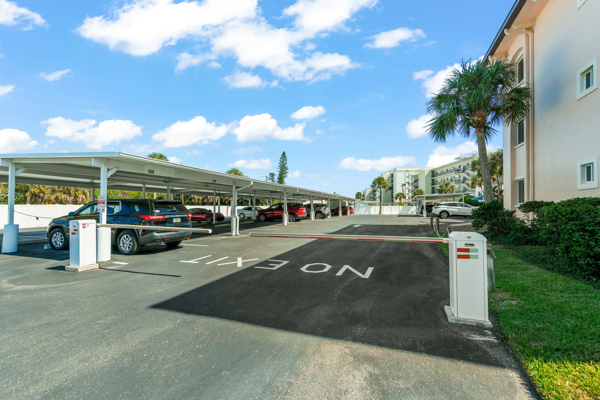 Een parkeerplaats met aanduidelijke uitgangsrijen, een overdekte parkeergarage en een gebouw met meerdere verdiepingen.